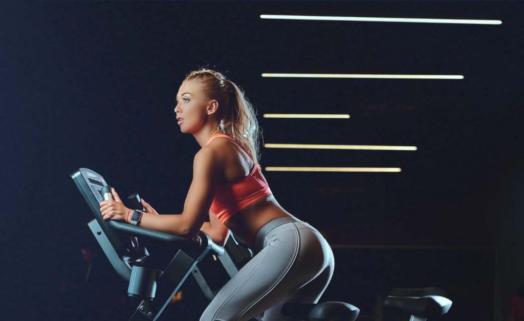 Woman exercising on stationary bike wondering if CicloZone, an indoor cycling app, is for her