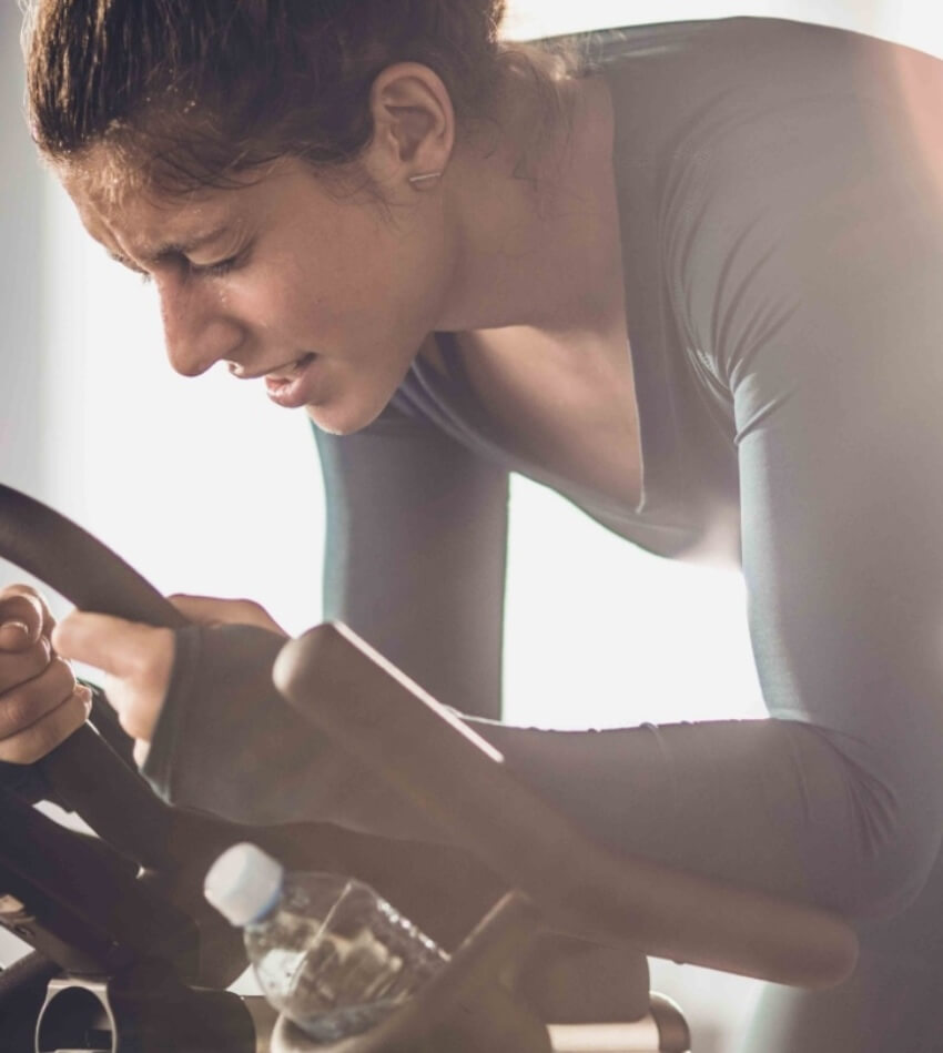 Woman cycling on an indoor stationary bike demonstrating easiness of using CicloZone, an indoor cycling app