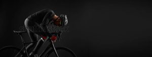 Man cycling a black bicycle with black gear with a black background