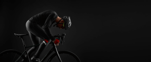 Man cycling a black bicycle in black gear with a black background