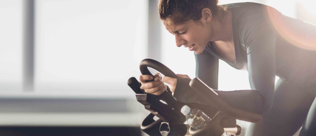 Woman cycling on an indoor stationary bike demonstrating easiness of using CicloZone, an indoor cycling app